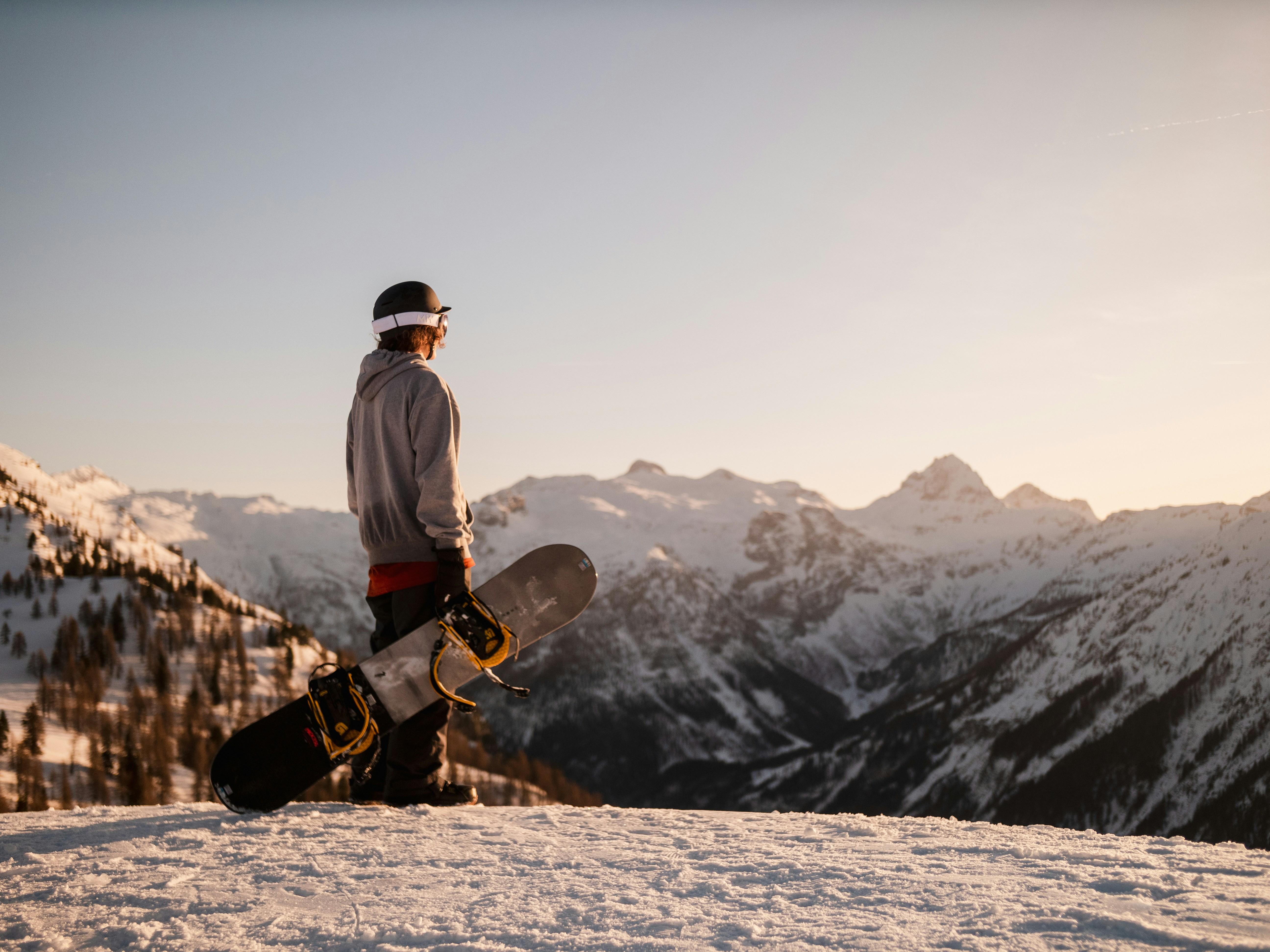 Snowboard instructor on a ridge at golden hour, mountains in the distance